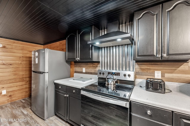 kitchen featuring wall chimney range hood, light wood-type flooring, stainless steel appliances, wooden ceiling, and wood walls