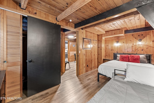 bedroom featuring beamed ceiling, wooden walls, light hardwood / wood-style flooring, and wood ceiling