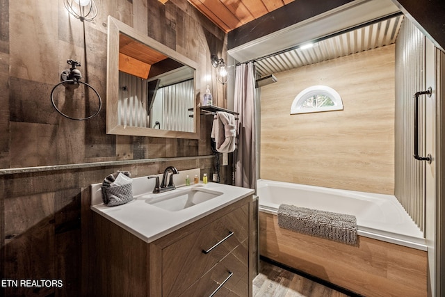 bathroom featuring wood-type flooring, oversized vanity, wood walls, and shower / bath combo with shower curtain