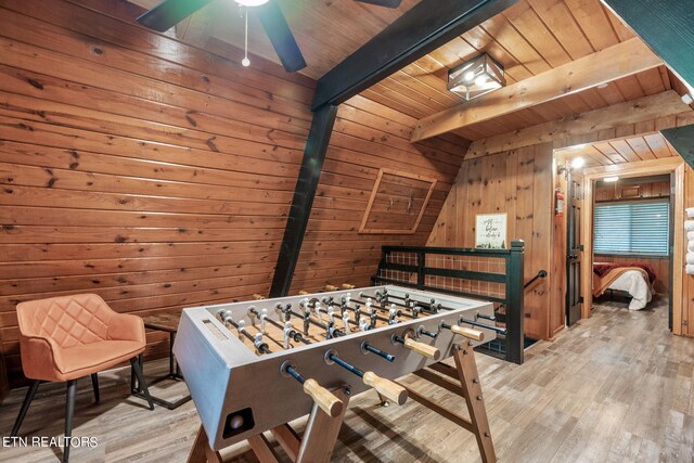 playroom with light hardwood / wood-style floors, ceiling fan, beam ceiling, wood ceiling, and wooden walls