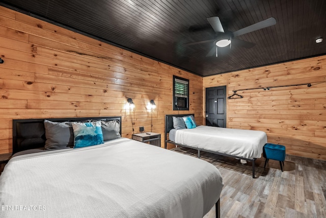 bedroom featuring wood ceiling, wooden walls, ceiling fan, and hardwood / wood-style floors