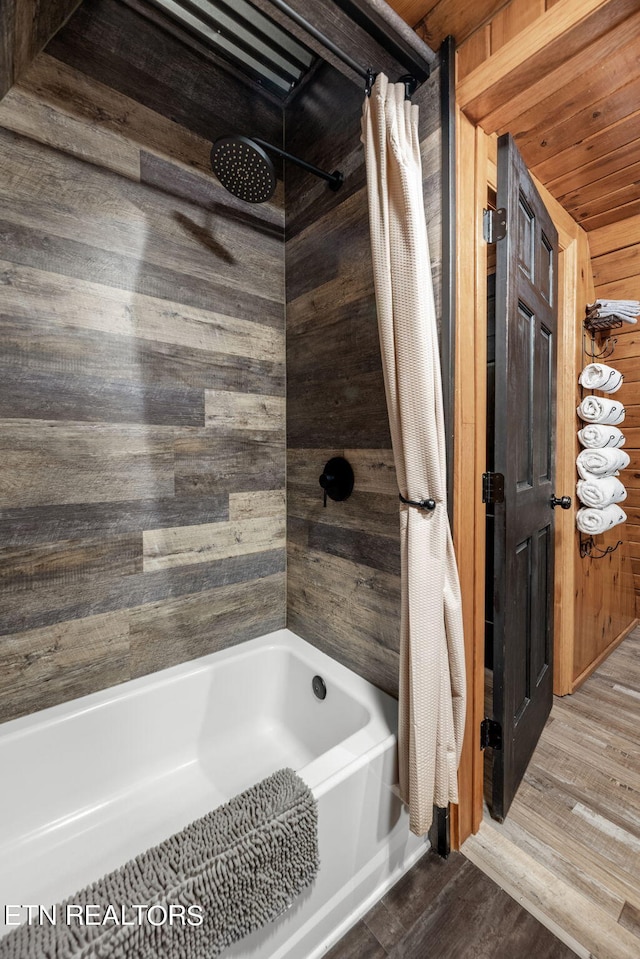 bathroom with wood walls, hardwood / wood-style floors, wooden ceiling, and shower / tub combo