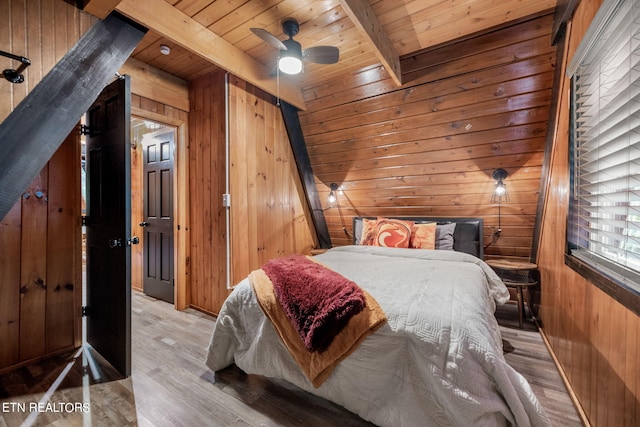 bedroom with light wood-type flooring, wood walls, and ceiling fan