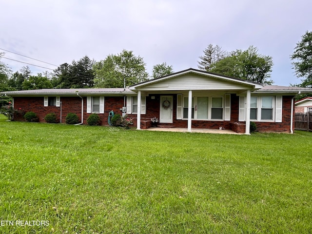 ranch-style home featuring covered porch and a front lawn