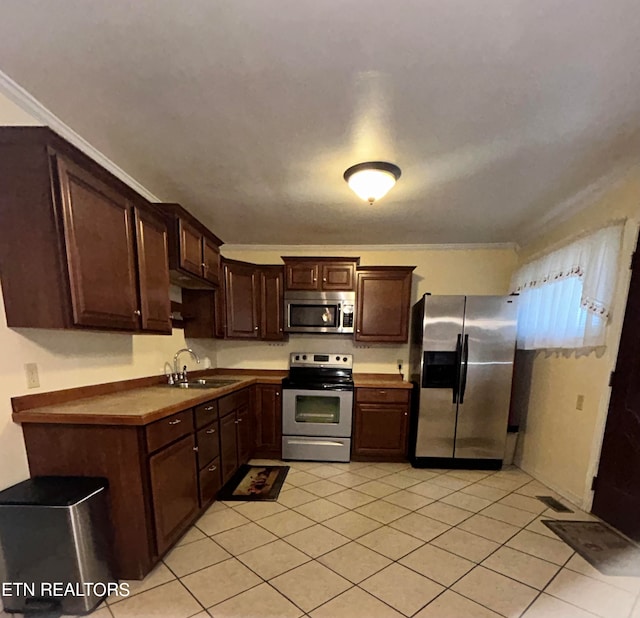 kitchen with appliances with stainless steel finishes, light tile patterned floors, dark brown cabinets, and sink