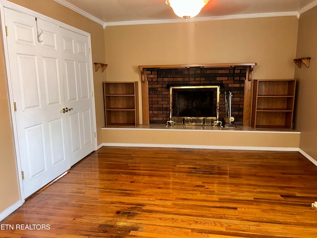 unfurnished living room with hardwood / wood-style flooring, a brick fireplace, and ornamental molding