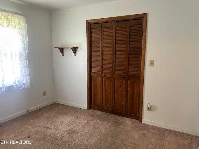 unfurnished bedroom featuring light colored carpet and a closet