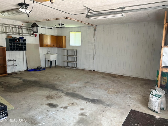 garage with a garage door opener, wooden walls, and sink