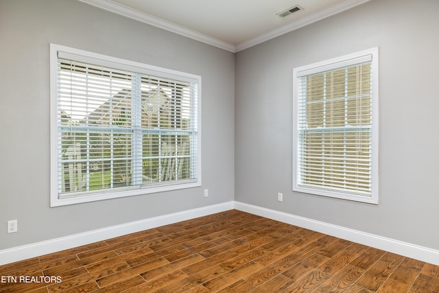 unfurnished room with a healthy amount of sunlight, ornamental molding, and hardwood / wood-style flooring