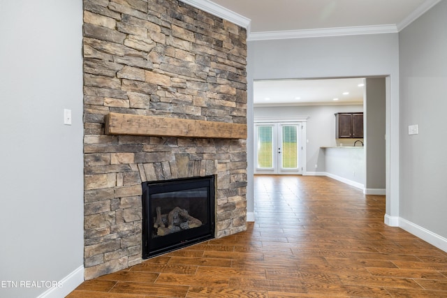 unfurnished living room with dark wood-type flooring, ornamental molding, and a stone fireplace