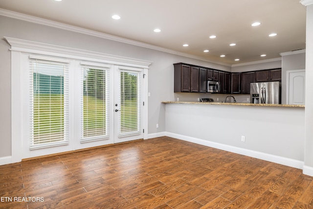 kitchen featuring hardwood / wood-style flooring, kitchen peninsula, stainless steel appliances, light stone counters, and dark brown cabinetry