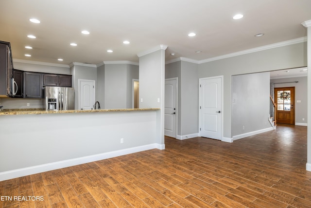 kitchen with light stone countertops, dark brown cabinetry, appliances with stainless steel finishes, and crown molding