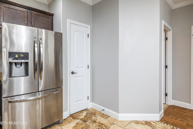 kitchen featuring stainless steel fridge, ornamental molding, and dark brown cabinetry