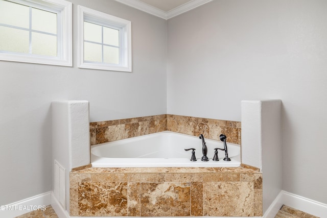 bathroom with ornamental molding and tiled tub