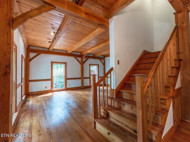 stairs featuring wooden ceiling, hardwood / wood-style flooring, beamed ceiling, and baseboards