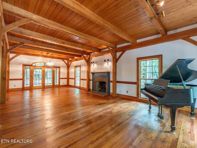 unfurnished living room featuring wooden ceiling, beamed ceiling, a brick fireplace, and hardwood / wood-style floors