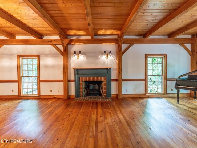 unfurnished living room with wood ceiling, a healthy amount of sunlight, wood-type flooring, and a brick fireplace