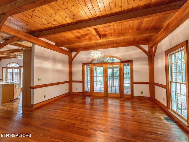 empty room featuring wooden ceiling, wood finished floors, baseboards, ceiling fan with notable chandelier, and beamed ceiling