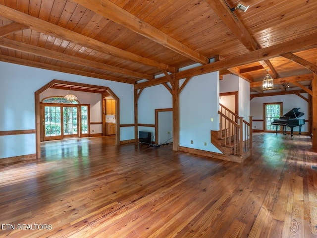unfurnished living room featuring stairs, wood ceiling, vaulted ceiling with beams, wood-type flooring, and baseboards