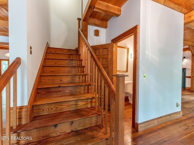 stairs featuring wood ceiling, beamed ceiling, and wood-type flooring