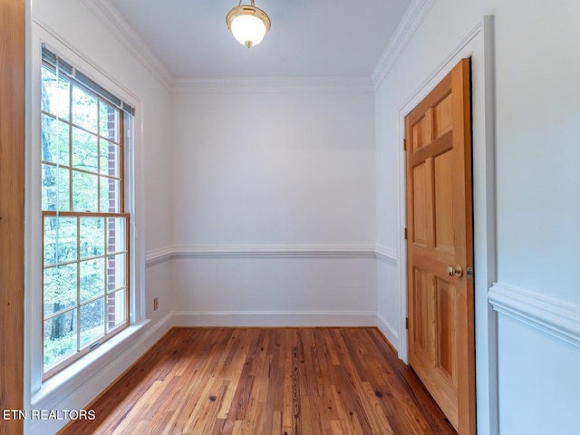 empty room with plenty of natural light, crown molding, baseboards, and wood finished floors