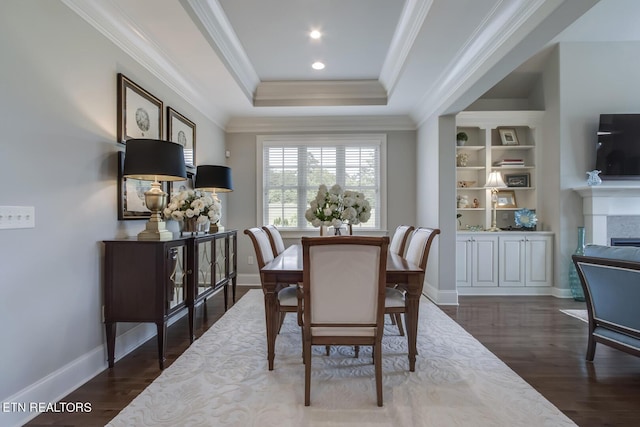 dining room with a tray ceiling, dark hardwood / wood-style flooring, and ornamental molding