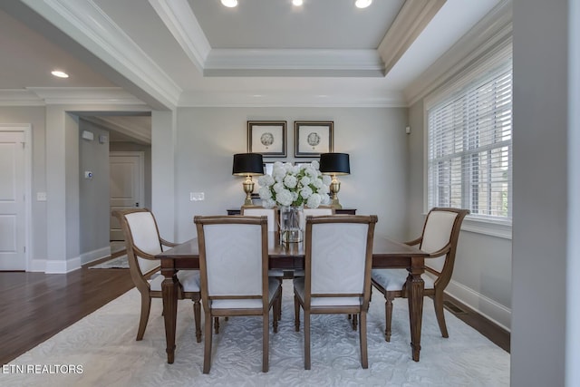 dining area with hardwood / wood-style floors, a tray ceiling, and crown molding