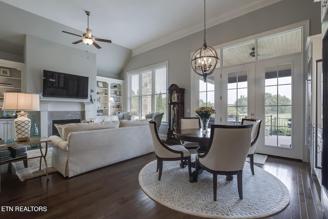 dining area featuring lofted ceiling, crown molding, built in shelves, dark hardwood / wood-style flooring, and ceiling fan with notable chandelier