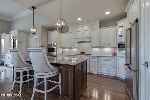 kitchen featuring a center island, pendant lighting, stainless steel appliances, and white cabinetry