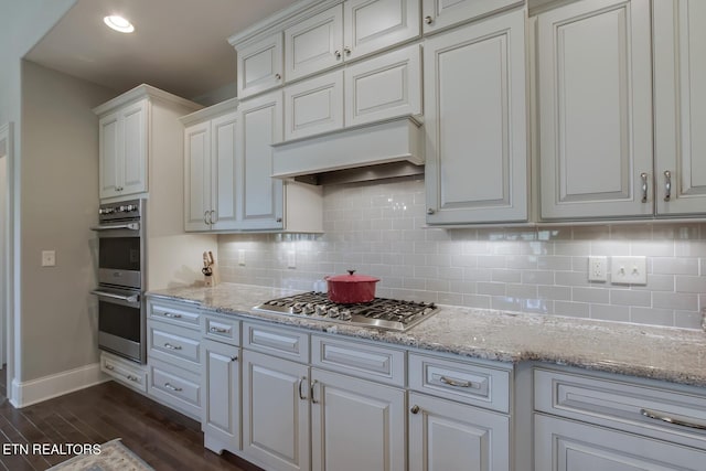 kitchen featuring light stone countertops, appliances with stainless steel finishes, white cabinetry, and dark wood-type flooring