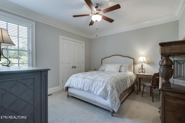 carpeted bedroom with ceiling fan, a closet, and crown molding