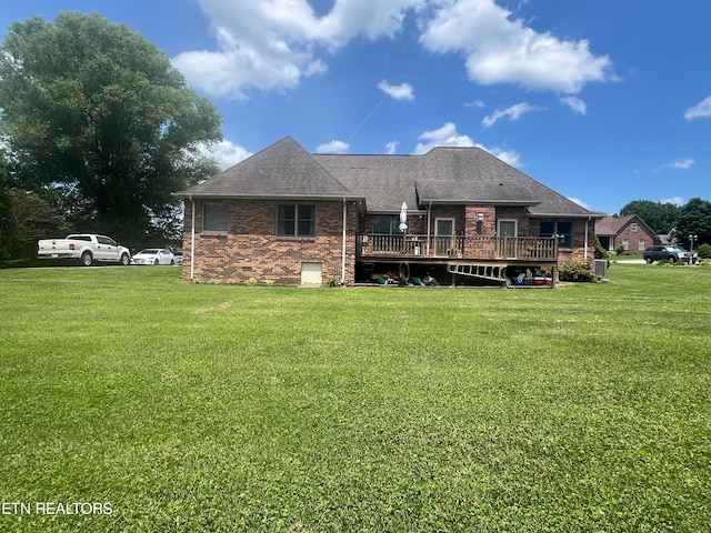 back of property with a wooden deck and a yard