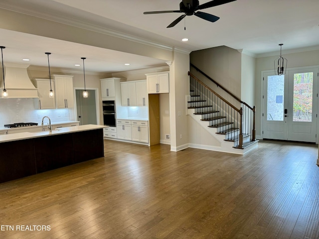 kitchen with custom exhaust hood, ceiling fan, gas stovetop, decorative light fixtures, and white cabinetry