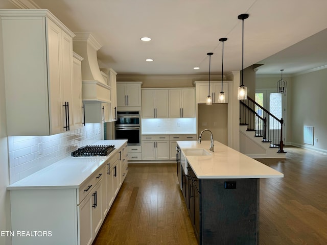 kitchen with white cabinets, a center island with sink, tasteful backsplash, and stainless steel appliances