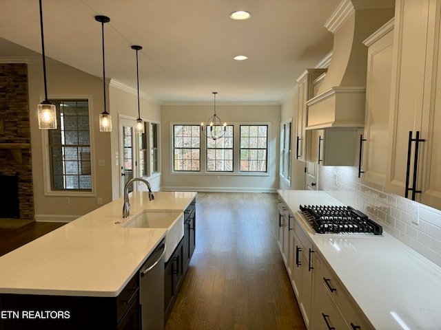 kitchen with appliances with stainless steel finishes, light stone counters, a kitchen island with sink, dark wood-type flooring, and white cabinets