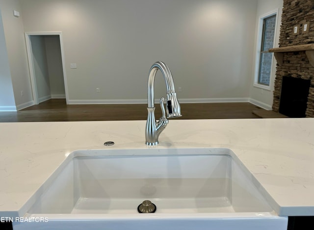 interior details featuring a fireplace, light stone counters, and sink