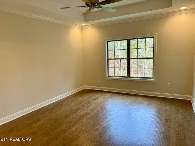 empty room featuring ceiling fan, dark hardwood / wood-style flooring, and a tray ceiling