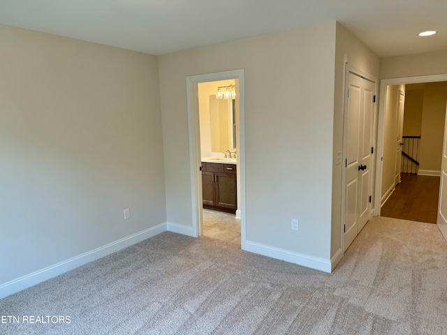 unfurnished bedroom featuring light colored carpet, sink, connected bathroom, and a closet