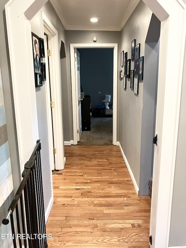 hallway with light wood-type flooring and ornamental molding