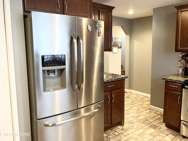 kitchen featuring dark stone counters, stainless steel appliances, and dark brown cabinetry