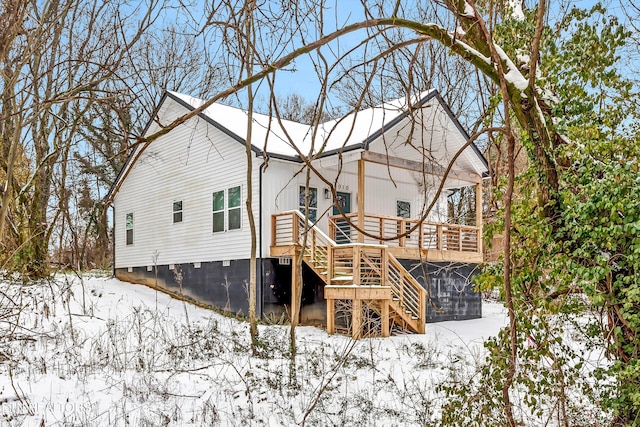 snow covered back of property featuring a deck