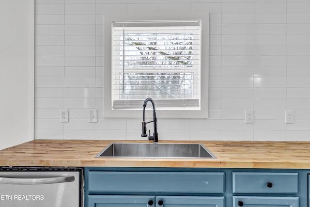 kitchen featuring sink, wooden counters, stainless steel dishwasher, and blue cabinetry