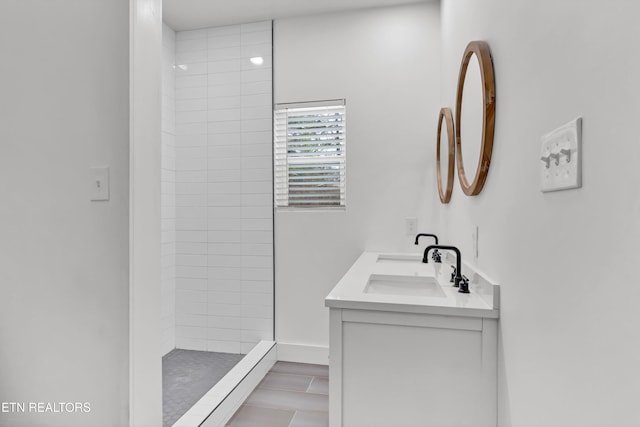 bathroom with a tile shower and vanity