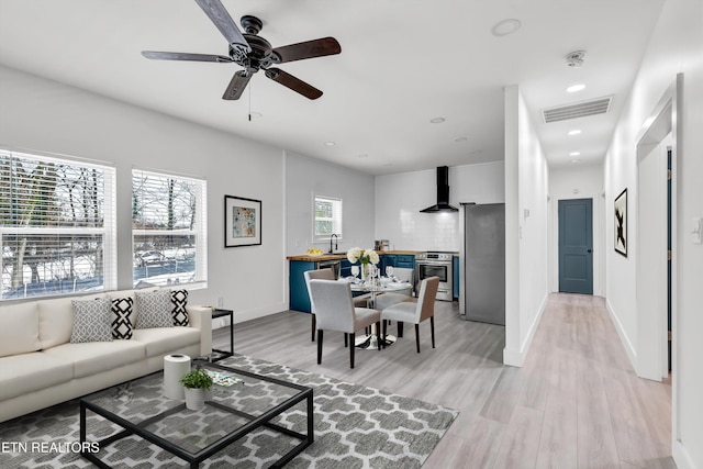 living room featuring ceiling fan, light hardwood / wood-style flooring, and sink