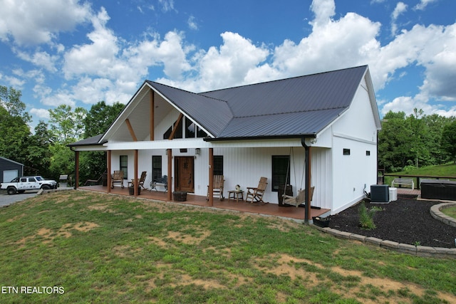 modern farmhouse style home featuring covered porch, a front yard, cooling unit, and a patio