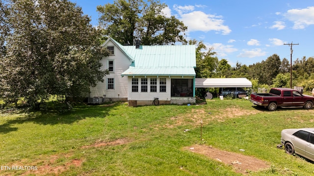 view of front facade with a front yard, central AC, a carport, and a sunroom