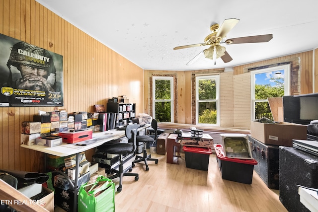 office featuring ceiling fan, wood walls, and light wood-type flooring