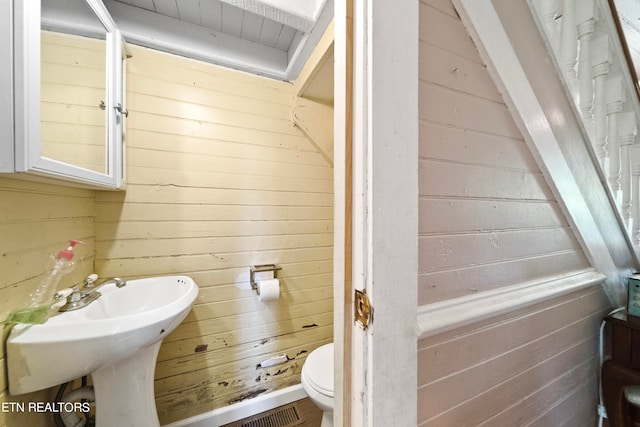 bathroom with wooden walls and toilet