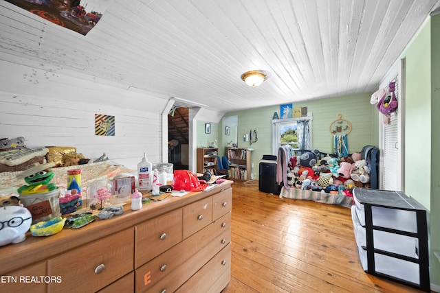 bedroom with light hardwood / wood-style floors and wood walls