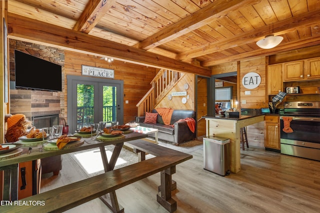 living room with wood ceiling, beamed ceiling, wooden walls, and a stone fireplace